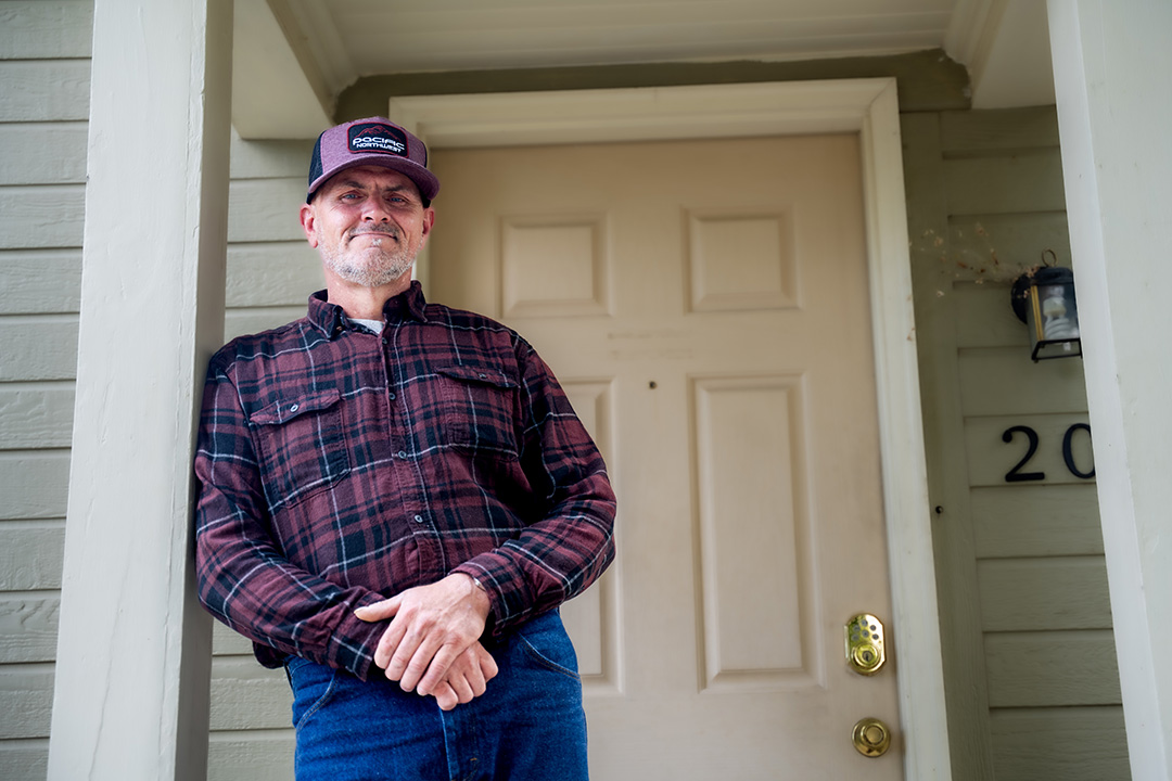 Jake smiling and standing in front of door.